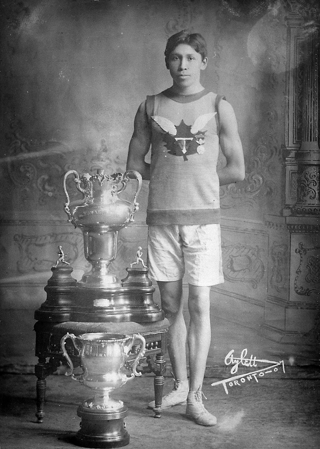 Tom Longboat avec ses trophées de course (22 avril 1907). Photo avec l’aimable autorisation de Bibliothèque et Archives Canada.
