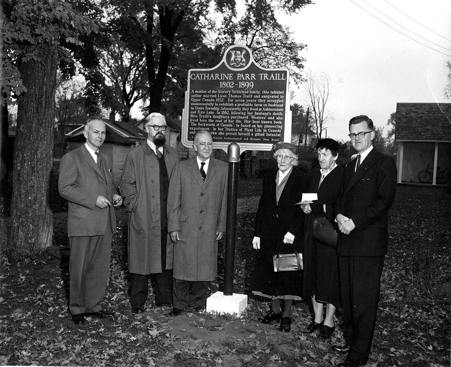 Le dévoilement de cette plaque provinciale en 1958 permet de rendre hommage à Catharine Parr Traill. Étaient présentes Mme Anne Atwood et Mme Anne Traill, les petites-filles de l’auteure. Était également présent (deuxième à partir de la gauche) le rédacteur de l’époque du Peterborough Examiner – Robertson Davies – qui devint, à son tour, un géant littéraire.