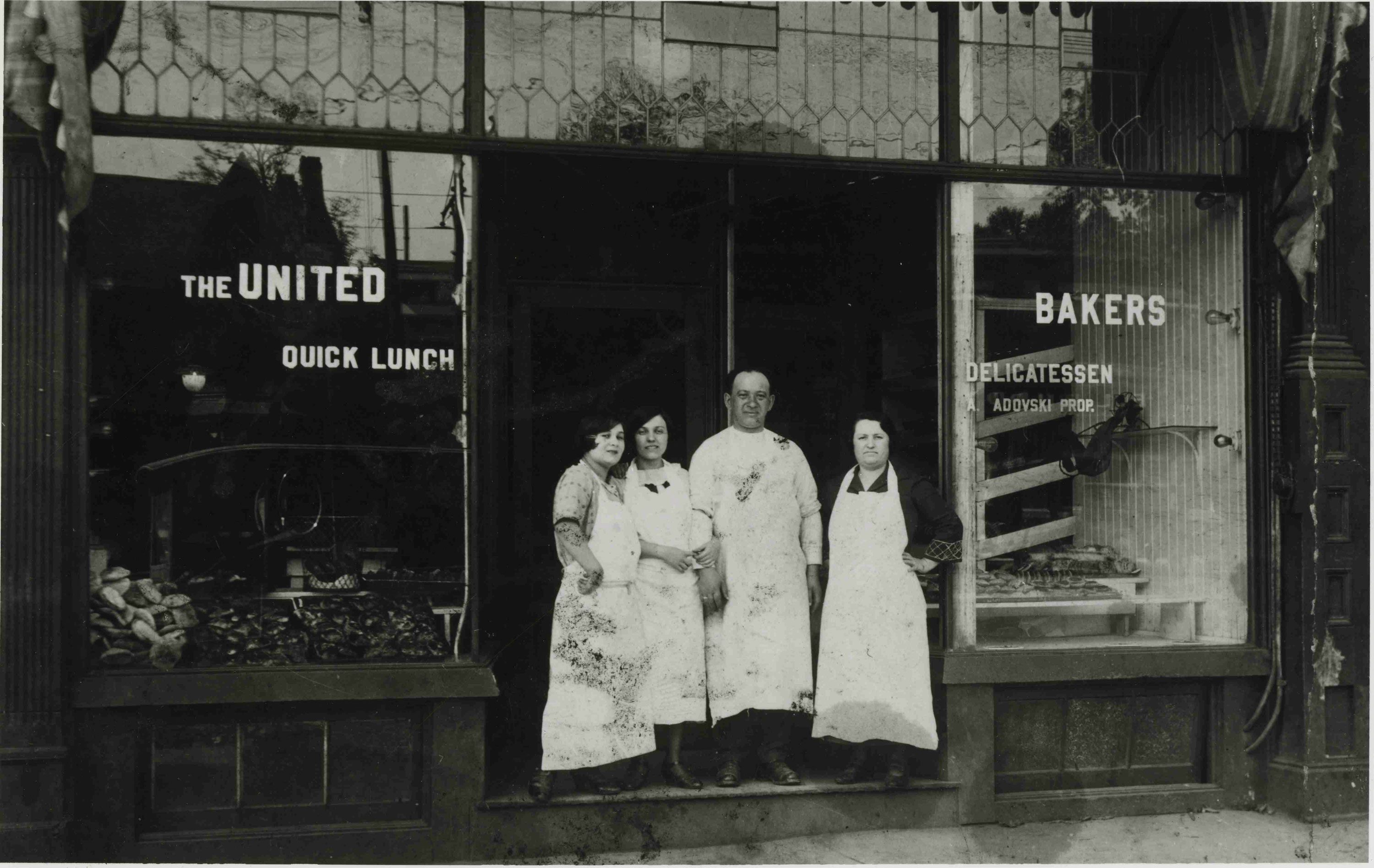 Photo en noir et blanc d’un homme et de trois femmes debout devant la porte du restaurant